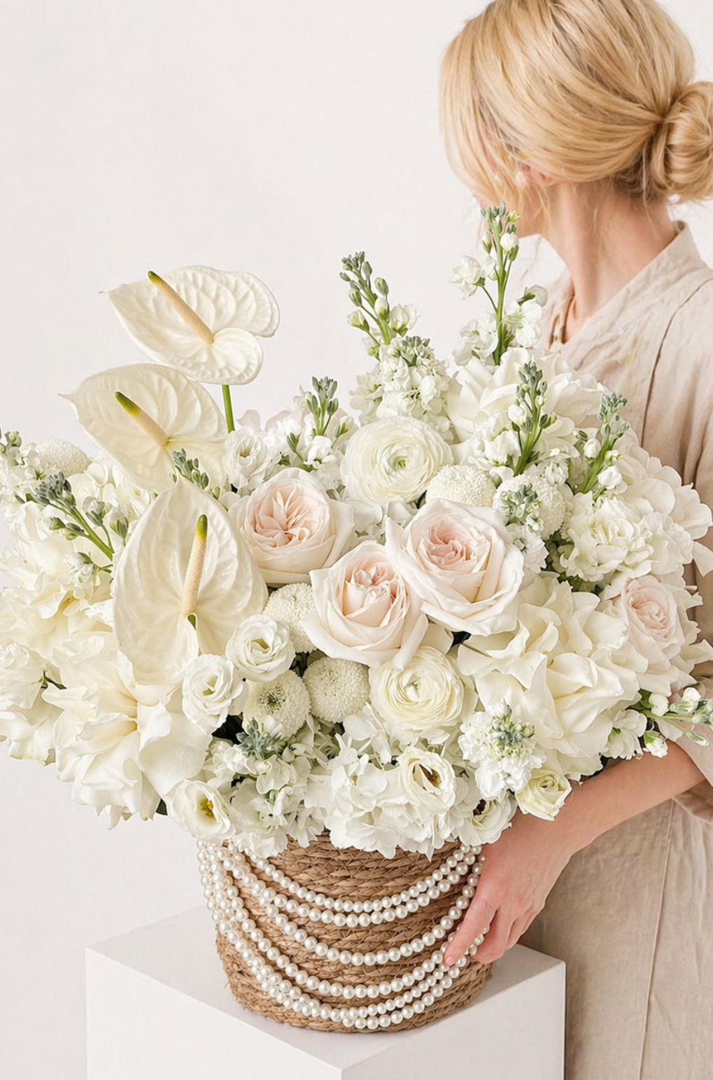 Ivory fresh flower arrangement with roses, anthuriums, and hydrangeas in a pearl-adorned basket