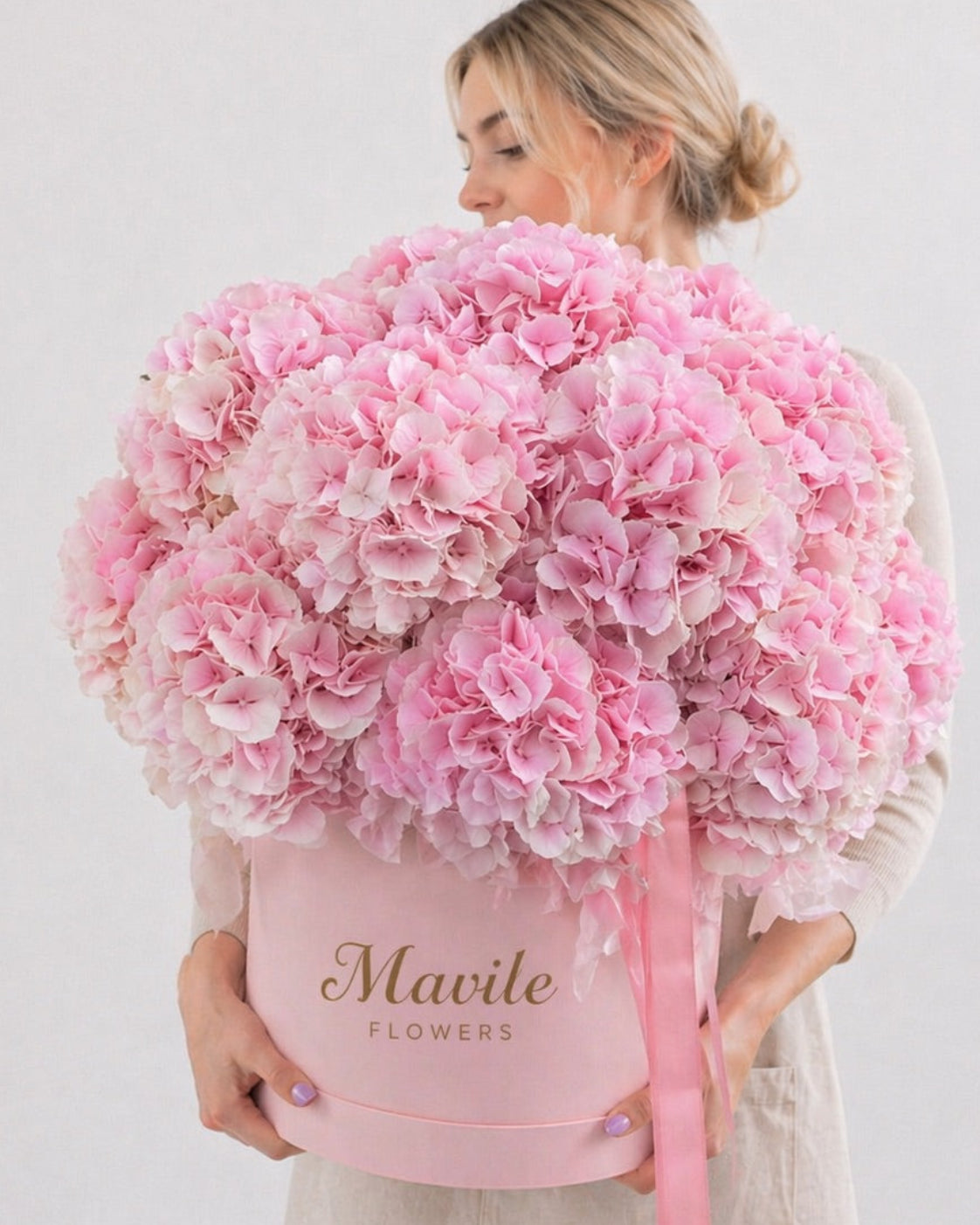 Fresh pink floral arrangement near me by FSMIA in a pink round box held by a woman