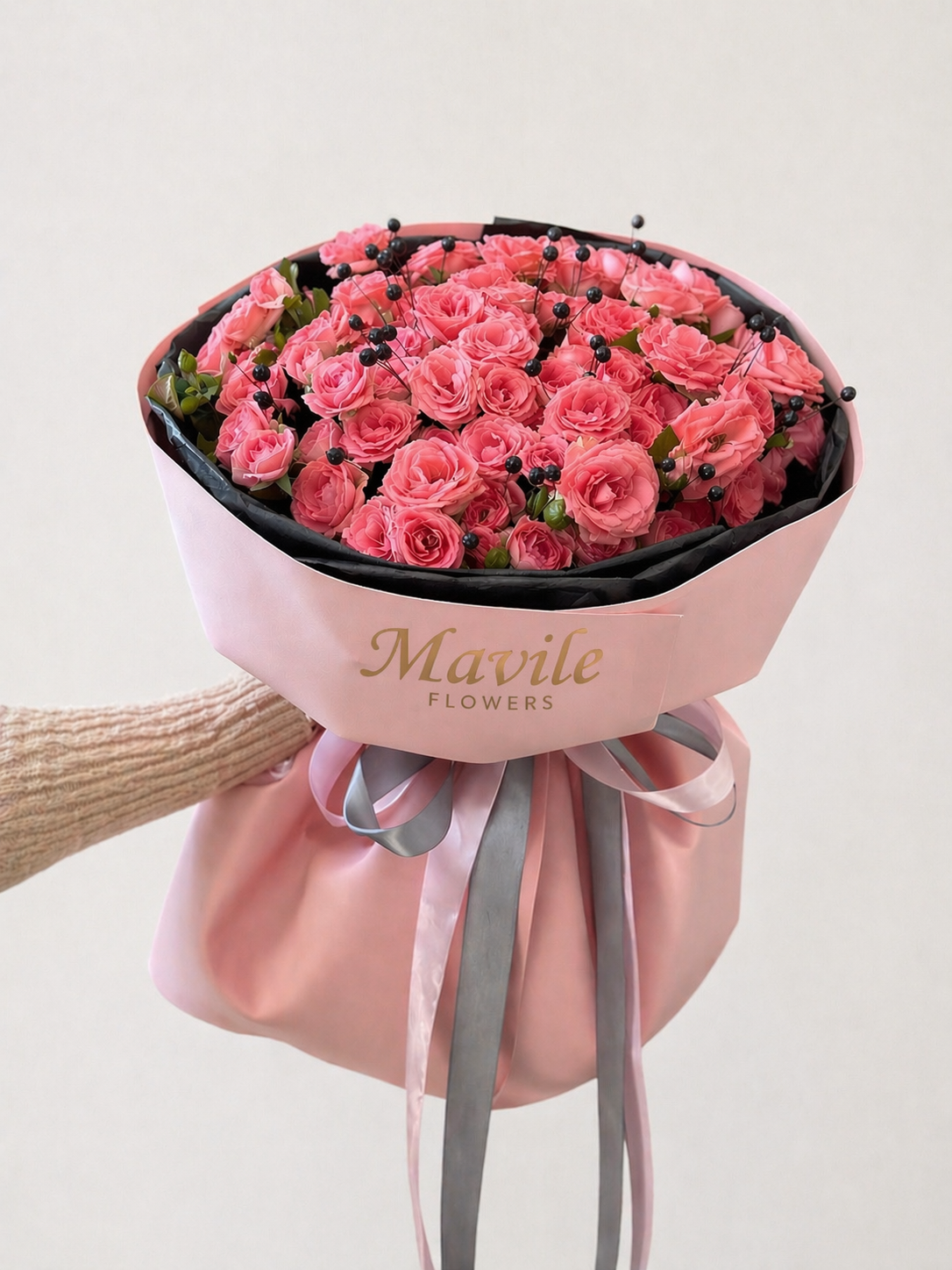 FSMIA pink rose bouquet wrapped in pink paper with gray ribbons held by hand